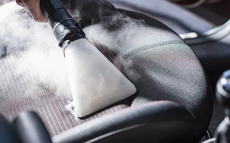 Technicien H₂O aspirant un siège de voiture